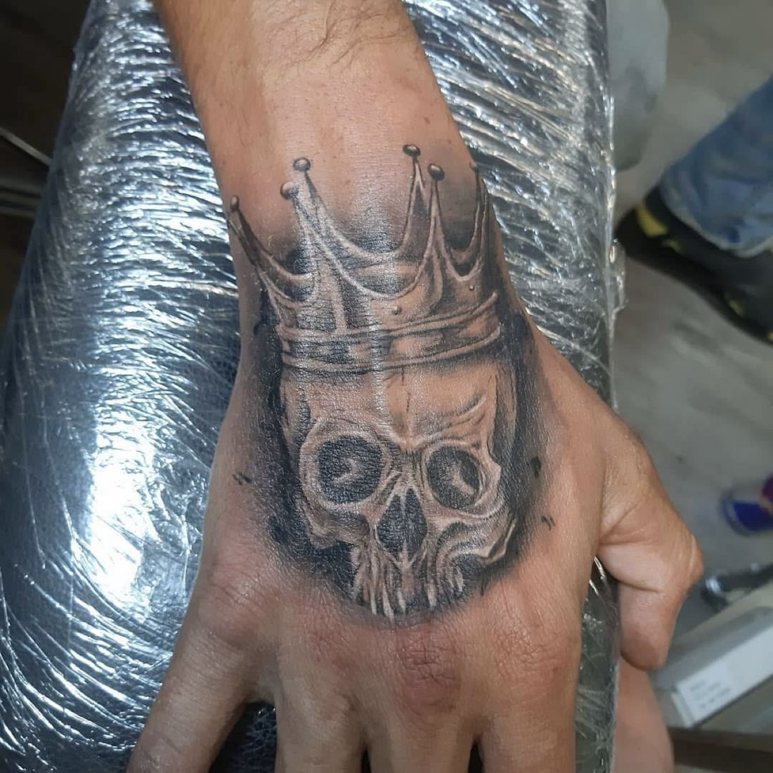 Tattoo: Black & grey realism — Crowned skull hand piece